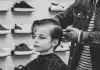 greyscale photo of boy having a haircut
