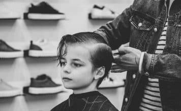 greyscale photo of boy having a haircut